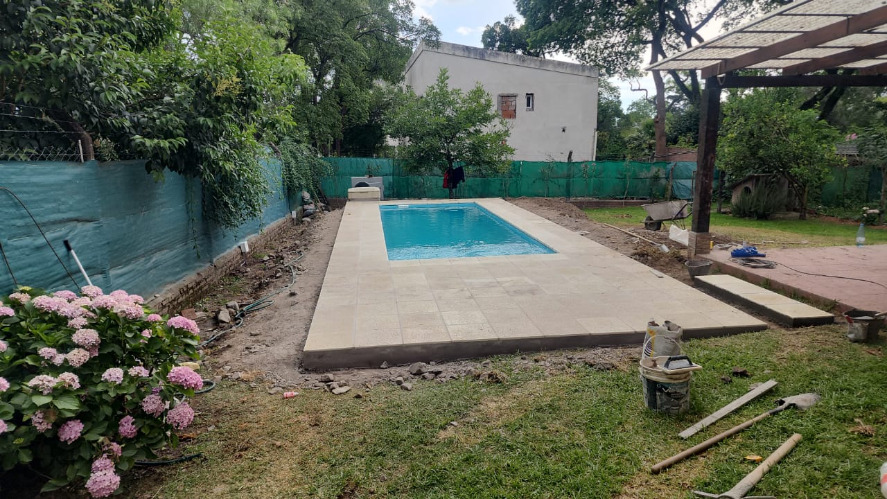 Piscina con solarium perimetral en jardin
