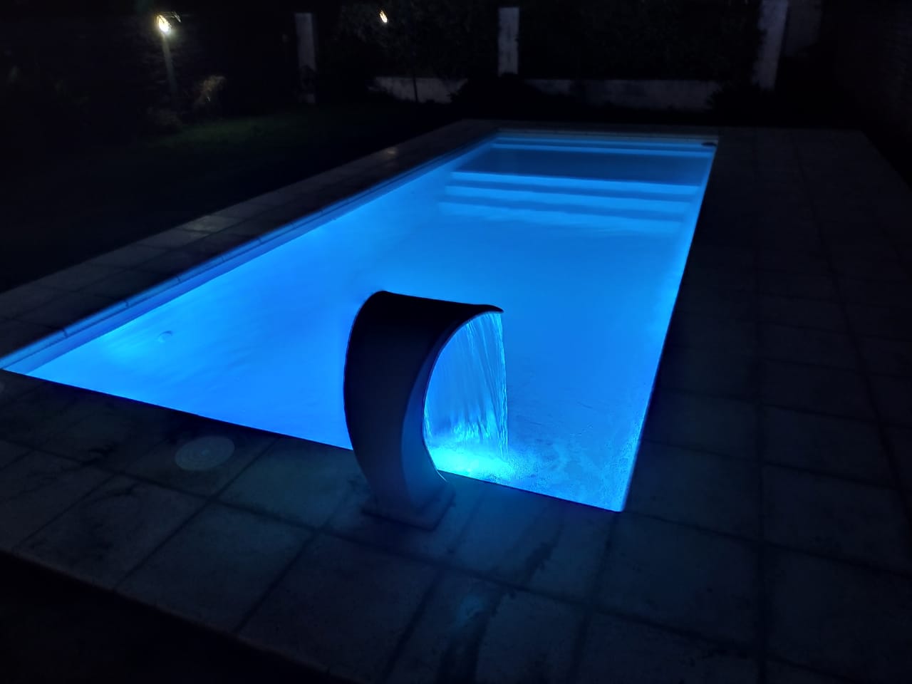 Piscina iluminada con cascada