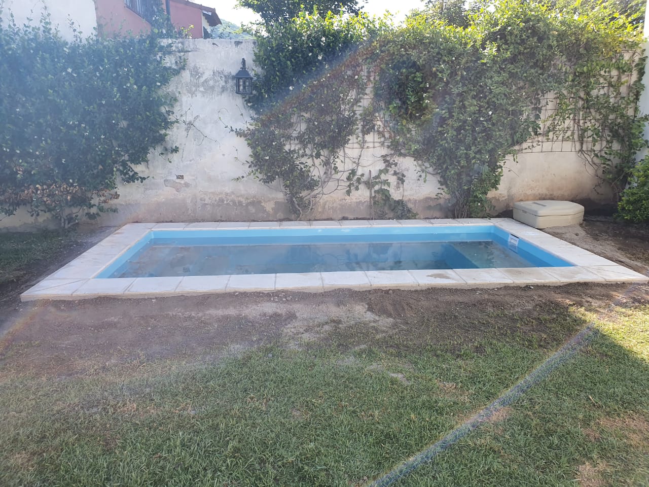 Piscina con borde perimetral y jardin
